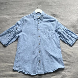 Ljusblå jeansskjorta med knappar - Säljer en ljusblå jeansskjorta med knappar framtill. Perfekt för en avslappnad och cool stil.