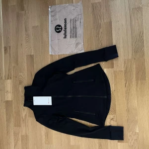 Lululemon Jacket - Lululemon jacka – storlek S passar delvis XS Helt ny med tag kvar. Aldrig använd, kommer i originalförpackning. Färg: Svart Superfin och bekväm – perfekt till träning eller vardag!
