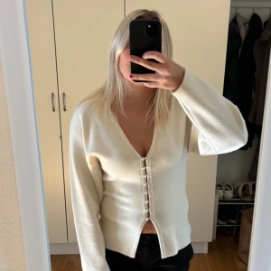 Krämvit kofta med pärlknappar - Säljer denna populära koftan från Gina tricot! Den har en v-ringning och snygga pärlknappar framtill. Koftan har lång ärm och är i ett mjukt material. 😊Storlek XS men passar mig som brukar ha S i tröjor! Slutsåld på Gina Tricots hemsida!