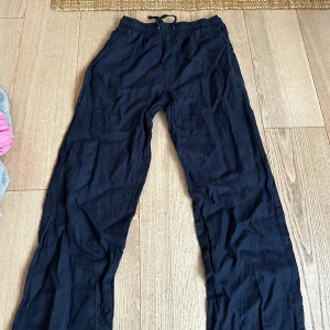 Mörkblå linnebyxor med snörning - Snygga mörkblå linnebyxor med avslappnad passform och elastisk midja med snörning. Perfekta för en chill och stilren look. Lätta och luftiga, passar grymt till sommaren eller när du vill ha det bekvämt.