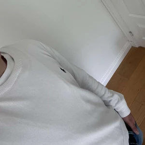 Vit långärmad tröja från Polo Ralph Lauren - Vit långärmad tröja från Polo Ralph Lauren med klassisk rund hals och broderad logga på bröstet. Tröjan är stickad i mjuk bomull och har ribbade muddar vid ärmslut och nederkant. Storleken är L men passar även M!!! Knappt använd och pris är diskuterbart!!!