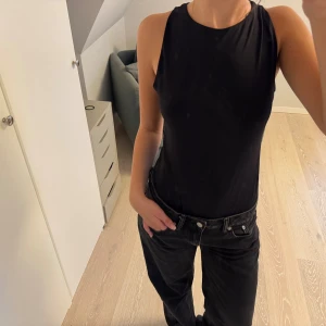 Svart ärmlös body Gina Tricot - Säljer en svart, ärmlös body från Gina Tricot i storlek L. Modellen har rund halsringning och är figurnära med en clean look. Perfekt att styla med jeans eller kjol för en enkel och snygg outfit. Säljer för att den inte kommer till användning!
