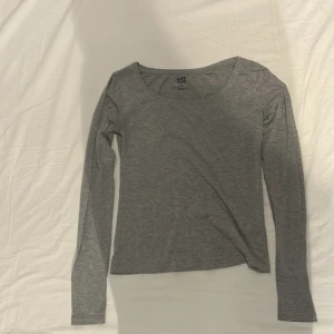 Grå långärmad topp från 157 - En basic grå långärmad topp från 157 i storlek XS. Tillverkad i en mjuk blandning av polyester, bomull och elastan som gör den stretchig och bekväm. Enkel design med rund halsringning och figurnära passform, perfekt att styla med jeans eller kjol.
