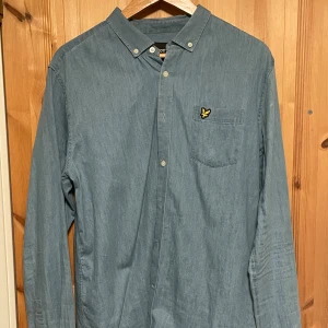 Jeansblå Lyle&Scott skjorta - Säljer en fin Lyle&Scott skjorta i storlek L. Skjortan är i ett jeansblått material. Skjortan är i nyskick.