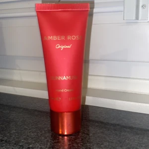 Amber Rose handkräm från SUNNAMUSK - Amber Rose Original handkräm från SUNNAMUSK i en snygg röd tub med gulddetaljer och metallisk röd kork. Perfekt att ha i väskan för mjuka händer med en lyxig doft av ros och amber.