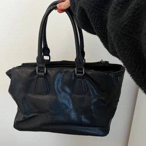 Svart handväska i vintage stil - En medelstor väska som rymmer mycket och har många fack. Den är svart och har en vintage stil, på insidan har den ett gulligt mönster. Ops! Den har några defekter, den har något slitet märke på utsidan och lite smutsig på insidan. Men de gör den bara mer vintage:)