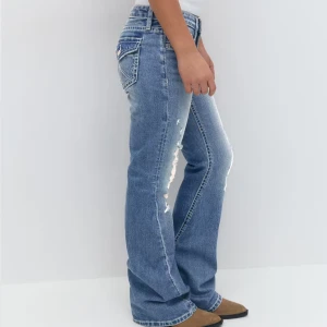 Blå bootcut jeans med slitningar - Säljer ett par blå bootcut jeans med snygga slitningar framtill och markerade bakfickor med dekorativa sömmar. Jeansen har låg midja. Kostar 430 När man köper dom helt nytt på Gina 