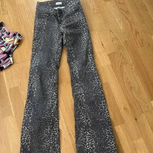 Leopardmönstrade bootcut jeans från Nelly - Snygga bootcut jeans från Nelly med leopardmönster i mörka toner. Byxorna har klassisk femficksdesign, knappgylf och är tillverkade i ett jeansmaterial. Perfekt för dig som vill sticka ut med ett coolt mönster och skön passform.