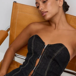  denim korsett från Gina Tricot - Säljer en denimtopp från Gina Tricot med markerade sömmar i kontrastfärg och metallspännen framtill. Modellen är axelbandslös och har en snygg, figurnära passform som ger en cool siluett. Säljer då de inte passar och alla lappar sitter kvar och den är aldrig använd❤️