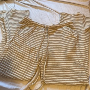 Randiga stickade byxor från SHEIN - Säljer ett par stickade byxor från SHEIN i storlek M. De är beige och vita med horisontella ränder och har en mjuk, virkad känsla. Byxorna har snörning i midjan och är perfekta för en chill och avslappnad look.