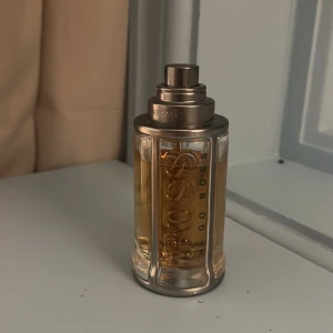 Hugo Boss The Scent herrparfym - Stilren parfym från Hugo Boss med modern design. Flaskans metalliska detaljer och tydliga logga ger ett exklusivt intryck. Perfekt för dig som vill sticka ut med en klassisk och trendig doft.