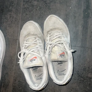 Nike Air Max 90 vita sneakers - Nike Air Max 90 sneakers i vitt med grå och beige detaljer. Klassisk design med synlig Air-enhet i sulan, snörning och rund tå. Ovandel i skinn och mocka med syntetinslag. Snygga och tidlösa sneakers som passar perfekt till streetwear.