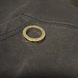 Stilren Ring från Chrome Hearts - Säljer en chunky silverring från Chrome Hearts med ikoniska korsdetaljer runt hela ringen. Ringen har en rund form och är tillverkad i massivt silver. Perfekt statement piece för dig som gillar edgy och cool stil. Passar inte mig, storlek 7/ 17mm, skulle tro att de passar någon med storlek 8/9. Pris kan diskuteras!