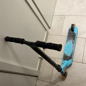 Oxelo Stunt Scooter - Stuntkickbike från Oxelo i blått och svart. Använd, med tydligt slitage på deckets griptape och repor på styret. Passar för tricks och lek. Robust konstruktion, hjul i gott skick. Perfekt för nybörjare eller som extra sparkcykel.