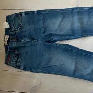 Blå jeans Ashley från Mos Mosh - Snygga blå jeans från Mos Mosh, modell Ashley. Jeansen har klassisk femficksdesign, råa kanter nertill och en lätt tvättad look. Croppade 3/4 längd. Stl 25 men passar 36-38.