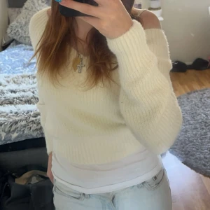 Vit offshoulder stickad tröja - Säljer en vit stickad tröja med offshoulder-design och långärmade ribbade ärmar. Tröjan är croppad och har en mjuk, mysig känsla som passar perfekt till jeans eller kjol. Enkel och stilren look som är lätt att matcha.