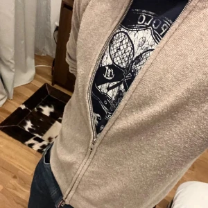 Beige Soft goat Kashmir Full zip - Snygg beige 100% kashmir kofta från Soft Goat med dragkedja framtill. Koftan är stickad i mjuk kashmir och har långärmad passform. Perfekt för dig som gillar stilrena och bekväma plagg med clean look. Priset är ej hugget i sten. Några små defekter på baksidan som inte märks av vid användning, går att fixa också (se bilden)