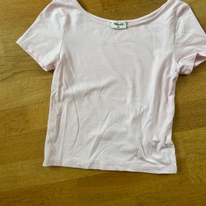 Ljusrosa topp från Kappahl - En basic ljusrosa topp från Kappahl med korta ärmar och rundad halsringning. Tillverkad i mjuk bomull, perfekt för en enkel och clean look. Passformen är normal och toppen är enfärgad utan detaljer.