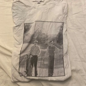 T-shirt 154  - Säljer en vit t-shirt från Fiore i storlek XS med ett stort svartvitt tryck på framsidan. De  tre står att den e xs men jag skulle säga att den passar 154