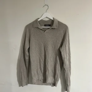 Beige stickad pikétröja Dressmann  - Säljer en beige stickad pikétröja från Dressmann Premium i storlek M. Tröjan har klassisk krage, ribbad struktur och långa ärmar. Perfekt för dig som gillar en clean och stilren look med lite retrovibbar. Skriv vid minsta fundering🍾💫