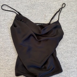 Svart linnetopp från Gina Tricot - Säljer en svart linnetopp från Gina Tricot som är perfekt för fest. Mjukt material och passar perfekt att matcha med jeans eller kjol.