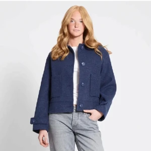 Mörkblå ulljacka med stora fickor - Snygg mörkblå jacka i ull med raka linjer och stora framfickor. Jackan har knappar framtill och på ärmsluten, samt en kort och boxig passform som ger en cool vibe. Perfekt att slänga över en t-shirt för en enkel men stilren look. I storlek M. Den är i bra skick, men använd ett par gånger. Skriv gärna om ni har några frågor!💗