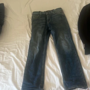 Blå Replay jeans straight fit - Snygga blå jeans från Replay med klassisk femficksdesign och raka ben. Jeansen har tydliga slitningar och kontrastsömmar, samt Replay-logga vid fickan och bak på linningen. Perfekt för dig som gillar en tidlös och cool stil.