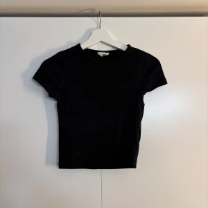 Svart och vit croppad topp - Två stilrena croppade toppar i svart och vitt med rund hals och korta ärmar, från Gina tricot.