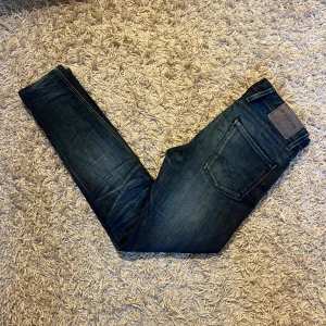 Replay Anbass slim jeans blå herr  - Snygga Replay Anbass jeans i mörkblå tvätt med slitningar och slim fit. Tillverkade i stretchig denim för extra komfort. Storlek W30, postas antigen samma dag som köp eller dagen därpå🙌
