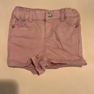 Ljusrosa jeansshorts från Denim by Skill - Säljer ett par ljusrosa jeansshorts från Denim by Skill. Shortsen har klassisk femficksdesign, knapp och hällor för bälte samt elastisk midja. Perfekta för varma dagar och ger en söt och trendig look.