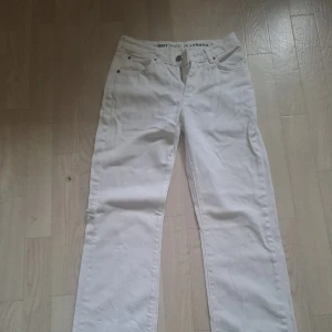 Vita raka jeans midwaist - Säljer ett par vita jeans med rak passform och klassisk femficksdesign. Midjan är midwaist och byxorna har dragkedja och knapp framtill. Perfekta till en clean och fräsch look. Materialet är jeans och färgen är helt vit.