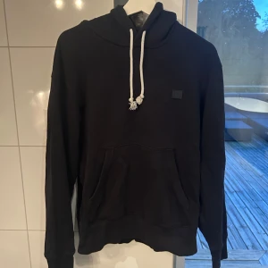 Svart hoodie från Acne Studios - Säljer en riktigt snygg svart hoodie från Acne Studios med vit snörning i huvan🍁Storlek M! Tröjan har en liten svart acnelogopatch på bröstet och är tillverkad i mjuk bomull. Nypris ligger runt 4000 kr och jag säljer för endast 899 kr💫I väldigt fint skick utan några skavanker