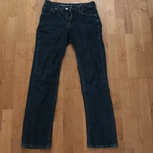 Mörkblå jeans straight - Storlek - waist: 27, Lengths: 32 Klassiska jeans i mörkblå tvätt med rak passform. Byxorna har fem fickor, knappgylf och tydliga sömmar. Perfekta för dig som gillar en tidlös och avslappnad stil. Jeansmaterialet är slitstarkt och passar till det mesta.