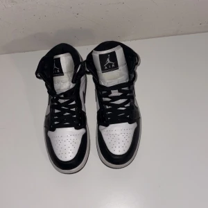 Jordans 1  - Säljer ett par Nike Air Jordan 1 sneakers i svart och vitt skinn. Klassisk high-top modell med svart swoosh, snörning och perforerad tå. Ikonisk Jordan-logga på sidan och tungans etikett. Perfekta för dig som vill ha en clean och tidlös look.dom är 40,5 men passar som 41-42