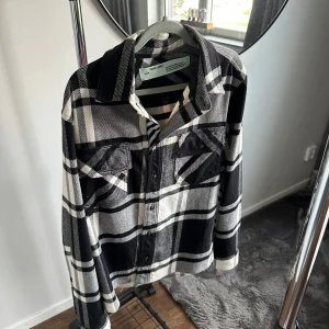  Off-White overshirt  - Säljer en fet overshirt från Off-White med svart, vit och grått rutmönster. Baksidan har en stor rosa grafisk print. Storlek XS. Bra skick. Oversized fit.