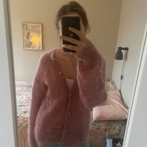 Egenstickad rosa kofta med knappar - Mysig rosa kofta med fluffig känsla. Tidigare köpt från Vinted och säljer då den inte används. Superfin, finns ingen storlek då den är egenstickad men skulle säga S/M. Den är ganska lång.