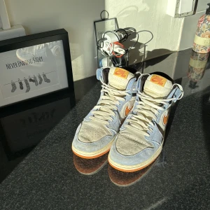 Nike Air Jordan 1 Zoom CMFT blå/orange - Säljer ett par Nike Air Jordan 1 Zoom CMFT med snygg färgkombo i ljusblå mocka, beige paneler och orange detaljer på swoosh och logga. Skorna har högt skaft, snörning och klassisk rund tå. Perfekta för dig som vill sticka ut med stilrena sneakers.