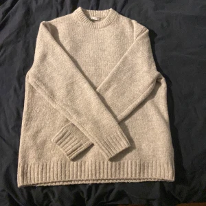 Beige stickad tröja från Zara - Mysig beige stickad tröja från Zara i storlek M. Tröjan har rund halsringning, ribbade muddar och nederkant samt långärmad passform. Perfekt för lager-på-lager under kyliga dagar.