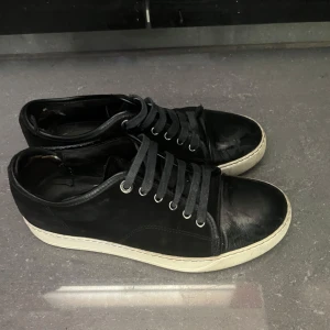 Svarta sneakers från Lanvin  - Säljer nu dessa svarta lanvin pga de har blivit för små för mig. Storleken är 40. Skorna har defekter på insidans som syns på tredje bilden och därför så billigt pris. Tveka inte på att höra av dig vid minsta fråga.