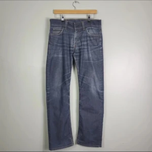 Levi's 506 blå jeans W31 L32 - Klassiska blå Levi's 506 jeans med raka ben och snygga slitningar. Jeansen har fem fickor, gul kontrastsöm och den ikoniska röda Levi's-taggen på bakfickan. Tillverkade i slitstarkt denim för en tidlös look.