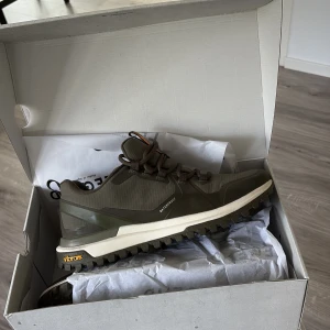 Bruna sneakers från Legend med Vibram-sula - Snygga bruna sneakers från Legend med robust Vibram-sula och vattentätt material. Skorna har snörning, orange detalj på plösen och häl, samt grovt mönstrad sula för extra grepp. Perfekta för dig som gillar outdoor och streetstyle.