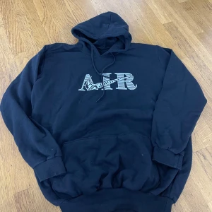 Svart Nike Air Jordan hoodie - Svart hoodie från Nike Air Jordan med stor vit AIR-logga och swoosh på bröstet. Klassisk känguruficka framtill, dragsko i huvan och ribbade muddar. Perfekt för dig som gillar streetwear och sportig stil.