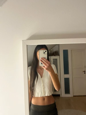 Vit croppad ribbad blus från H&M Divided - Säljer en vit croppad blus från H&M Divided i storlek XS. Toppen har korta ärmar, krage och knappar framtill. Materialet är ribbad och mjukt, vilket ger en snygg struktur. Perfekt för dig som gillar stilrena och enkla plagg med lite edge. Storlek xs.