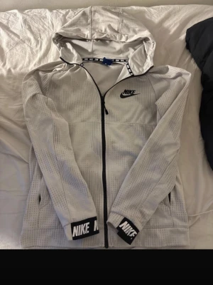 Vit Nike dress - Säljer ett par vita mjukisbyxor från Nike med diskret randigt mönster och svart Nike-logga på benet. Byxorna har elastisk midja med dragsko och är tillverkade i mjukt bomullsmaterial. Perfekta för chill eller träning. Tröjan tillhör byxorna.