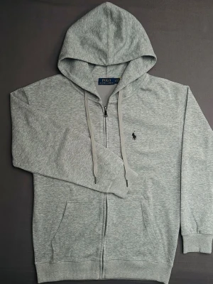 Grå hoodie från polo Ralph lauren  - Snygg grå hoodie med dragkedja från polo Ralph lauren med svart broderat märke på framsidan. Bra skick endast testat på en gång 