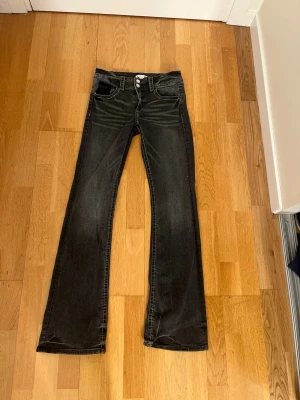 Svarta bootcut jeans från Gina Tricot - Snygga svarta jeans från Gina Tricot i storlek 170. Modellen har bootcut-ben och klassisk femficksdesign med dubbla knappar i midjan. Jeansen har en mörk tvätt och är gjorda med lite stretch för skön passform.