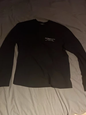 Svart långärmad tröja från  Axel Arigato - Svart långärmad tröja från Axel Arigato med vit textprint både fram och bak. Tröjan är tillverkad i  bomull och har en stilren design. Storlek M. 