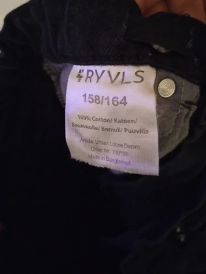 Svarta loose fit jeans från RYVLS - Säljer ett par svarta jeans från RYVLS i storlek 158/164. Modellen heter Urban Loose Denim och har en rak, loose passform med klassisk femficksdesign. Tillverkade i 100% bomull för en skön och slitstark känsla. Perfekta till sneakers och hoodie.