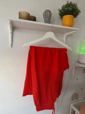 Orange mjukisbyxor med snörning - Snygga orange mjukisbyxor med elastisk midja och snörning längst ner vid bensluten. Byxorna har en loose passform och är gjorda i mjukt bomullsmaterial, perfekta för chill dagar. Färgen är riktigt klar orange och de har en enkel, stilren look.