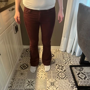 Vinröda manchesterbyxor från Only - Snygga vinröda manchesterbyxor från Only med bootcut-ben och klassisk femficksdesign. Byxorna har låg midja och är tillverkade i mjuk manchester, vilket ger en retro och trendig vibe. Perfekta för dig som vill sticka ut med färg och struktur.